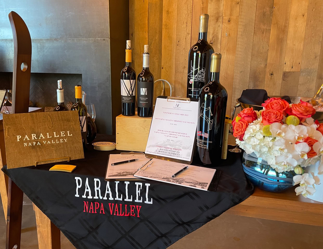 Display of Parallel Wines bottles with flowers and tasting notes at Napa Valley event.