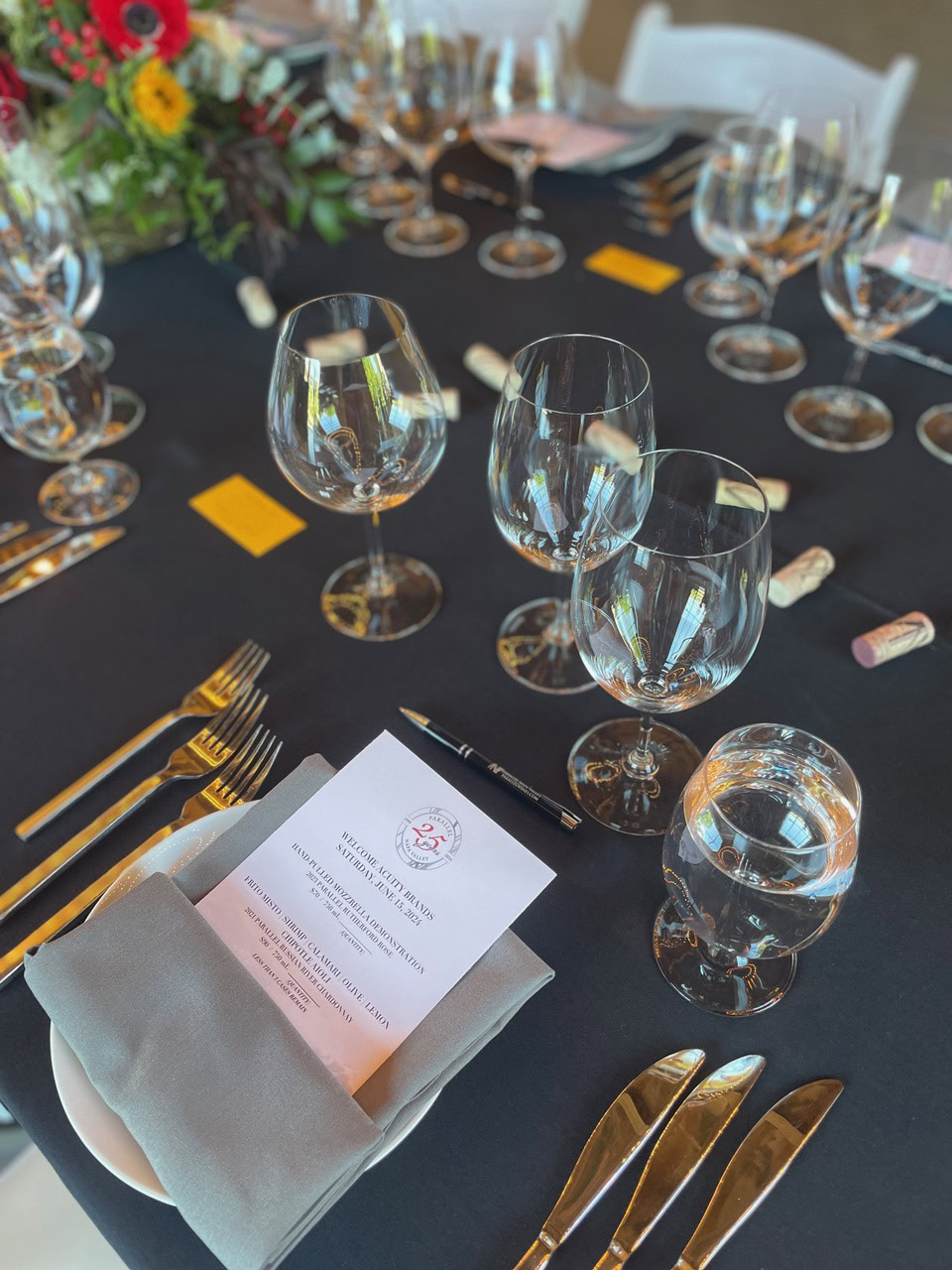 Sophisticated wine tasting table with glasses, menu, and floral centerpiece for Parallel Wines event.