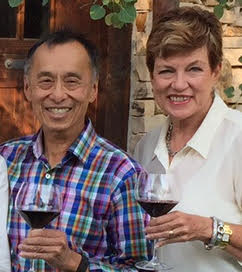 Two people enjoying red wine at Parallel Wines, smiling and holding glasses, in a cozy, rustic setting.